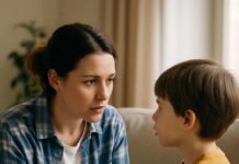 Disciplina Positiva: perchè ti cambia la vita Madre inginocchiata di fronte al figlio piccolo mentre gli parla con attenzione in un soggiorno luminoso.